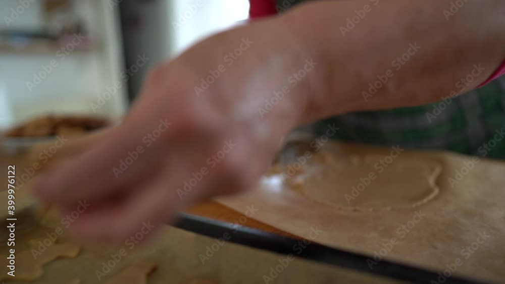 Baking tray with gingerbread cookies. Home cooking recipes. The weary hands of a female baker lay out the cookies on greaseproof paper for baking Baking tray with gingerbread cookies. Home cooking recipes. The weary hands of a female baker lay out the cookies on greaseproof paper for baking