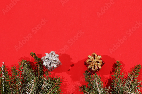 Fir branches lie on a red background decorated with Christmas gifts.