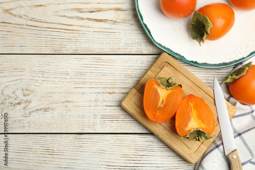 Tasty ripe persimmons on white wooden table, flat lay. Space for text