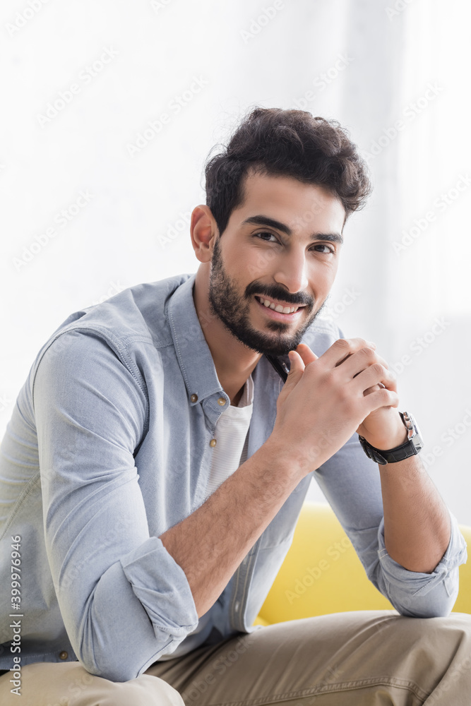 young hispanic man looking at camera while sitting at home young hispanic man looking at camera while sitting at home