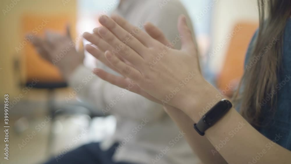 Side view of unrecognizable Caucasian man and woman sitting indoors and clapping. Young people cheering breakthrough or achievement. Side view of unrecognizable Caucasian man and woman sitting indoors and clapping. Young people cheering breakthrough or achievement.