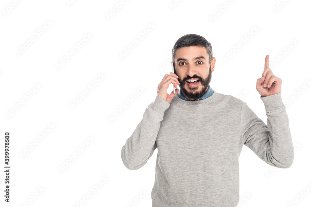 Fototapeta premium excited hispanic man showing idea gesture while talking on smartphone isolated on white