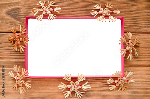 The white rectangle is surrounded by straw snowflakes. Warm wood background