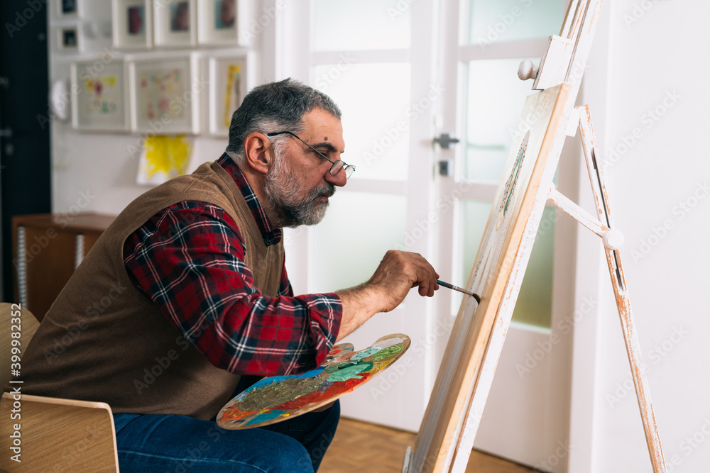 senior man painting picture at home senior man painting picture at home
