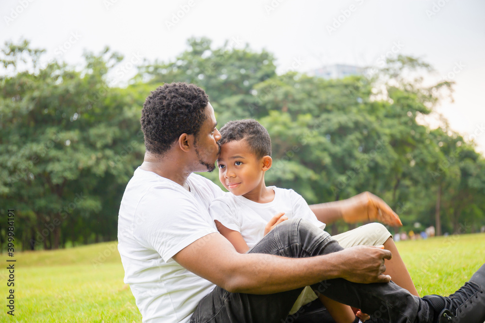 Happy African American father while hug and carry his son, Dad was kissing his son in the park, Joyful black family concept. Happy African American father while hug and carry his son, Dad was kissing his son in the park, Joyful black family concept.