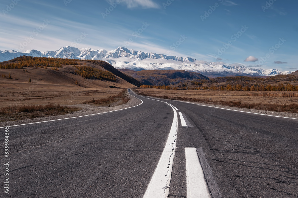 Asphalt road in amazing mountains. Snowy peaks on background