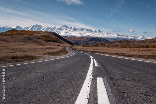 Asphalt road in amazing mountains. Snowy peaks on background