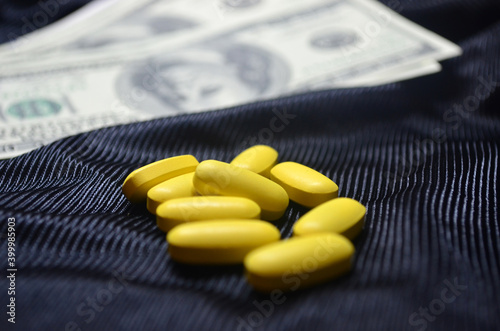 Yellow pills on a background of dollars. Expensive treatment, medicine. Drugs, prohibited substances, psychotropics, coronavirus