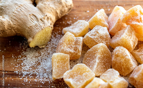 Close up of home made ginger candies and fresh ginger with sugar on wooden table.  photo