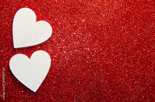 Valentines day concept. White decorative Hearts on red shiny background with copy space. Shiny sparkle metallic glitter texture. Top view  flat lay.