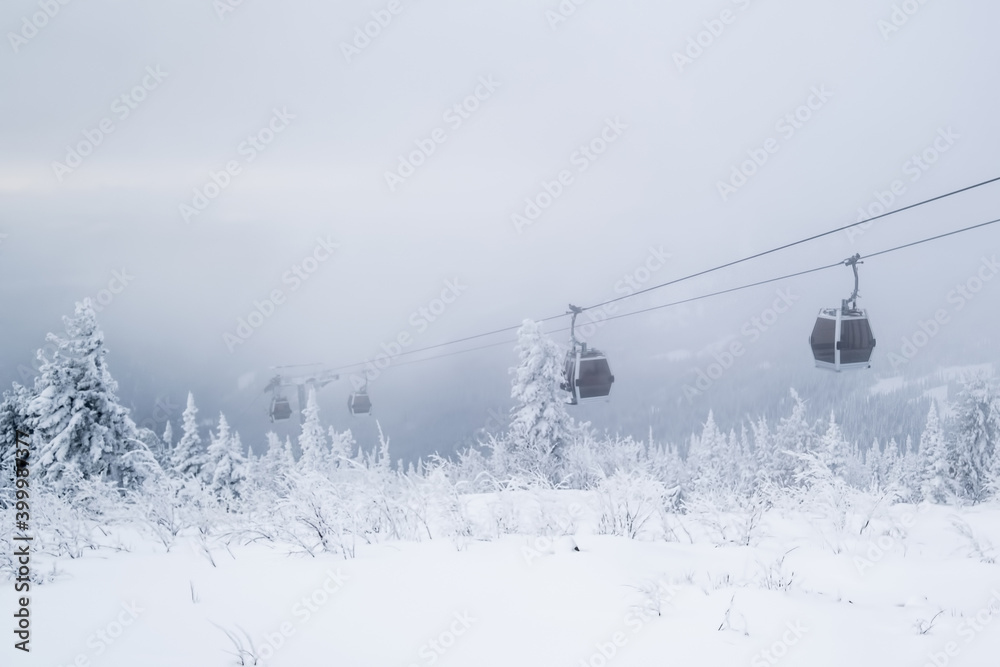 Gondola lift in the ski resort on snow covered slop, winter trees, mountains landscape Gondola lift in the ski resort on snow covered slop, winter trees, mountains landscape