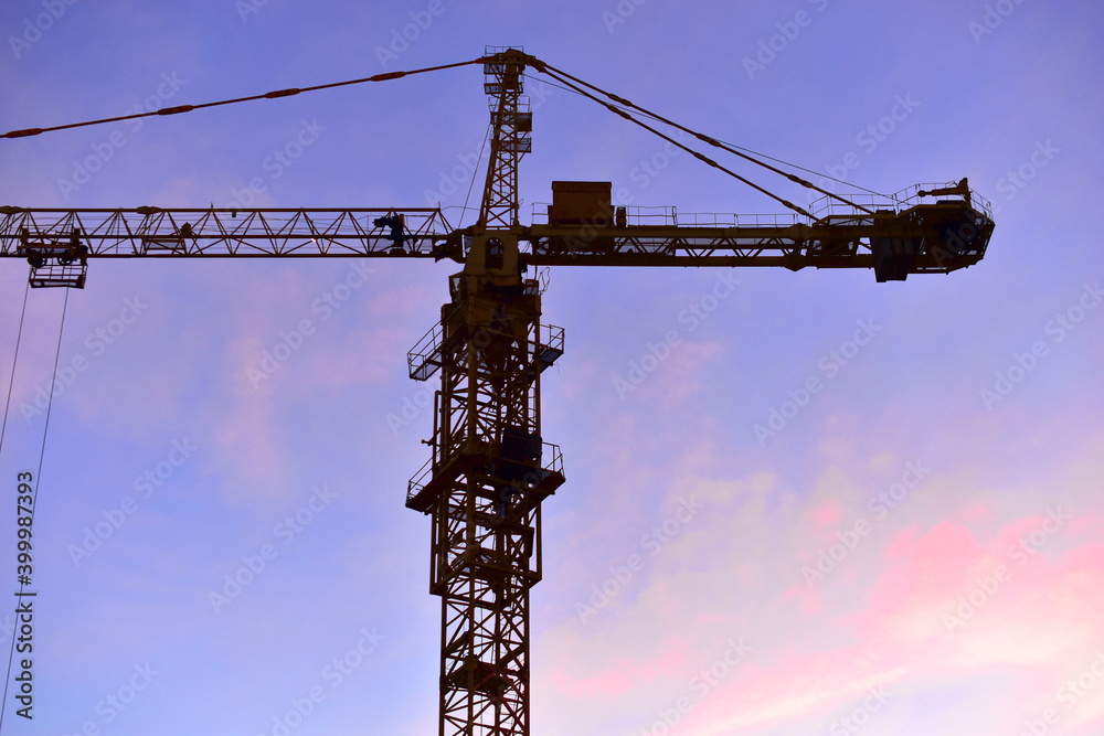 yellow construction tower crane on the background of the evening sky yellow construction tower crane on the background of the evening sky