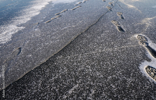 trail of human footprints on a snow-covered ice lake