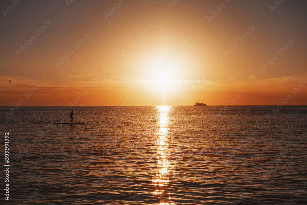 Sup surfer silhouette on beautiful sea sunset