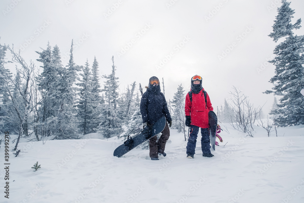 Portrait of Female snowboarders in snowy fir forest during snowfall winter day