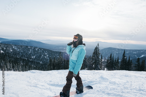 Young Female snowboarder on mountain top with beautiful landscape on background
