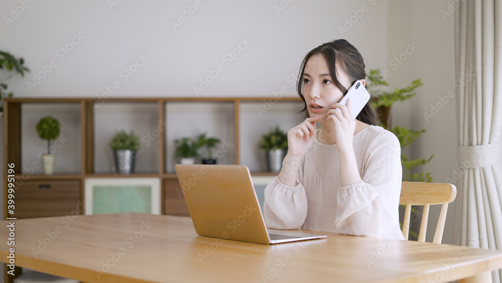 電話をしながらラップトップを使う若い女性 電話をしながらラップトップを使う若い女性