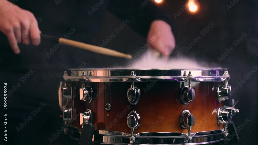 Man playing on snare drum with drumsticks. Closeup.
