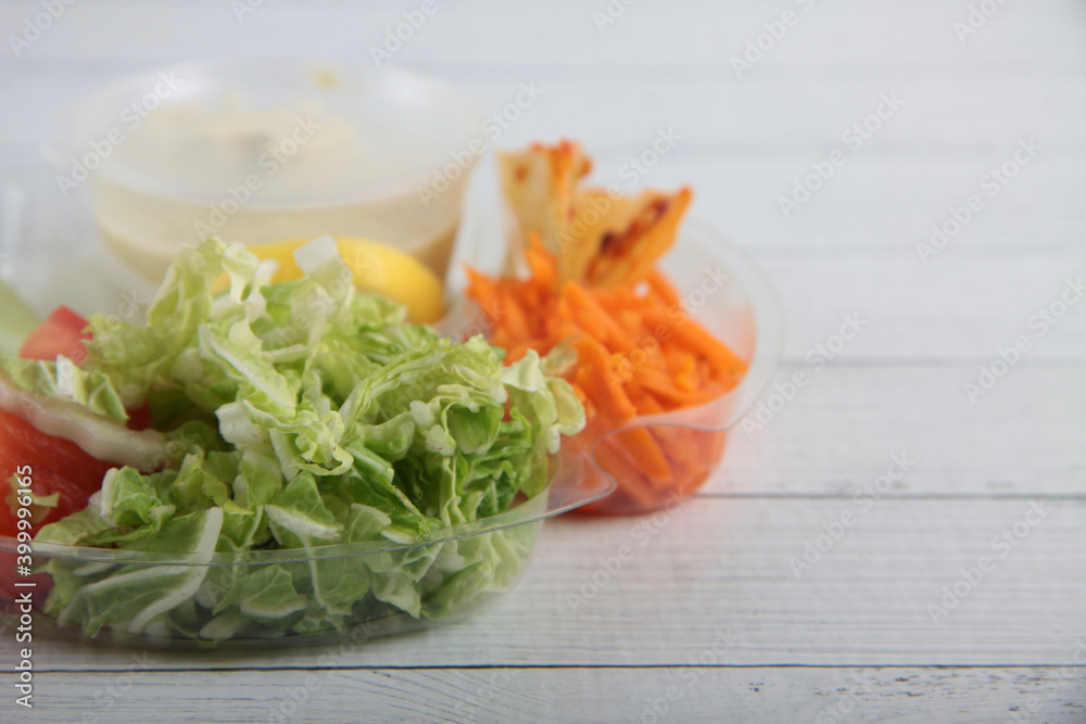 shop delivery concept - salad ingredients in a bowl on white wooden background shop delivery concept - salad ingredients in a bowl on white wooden background