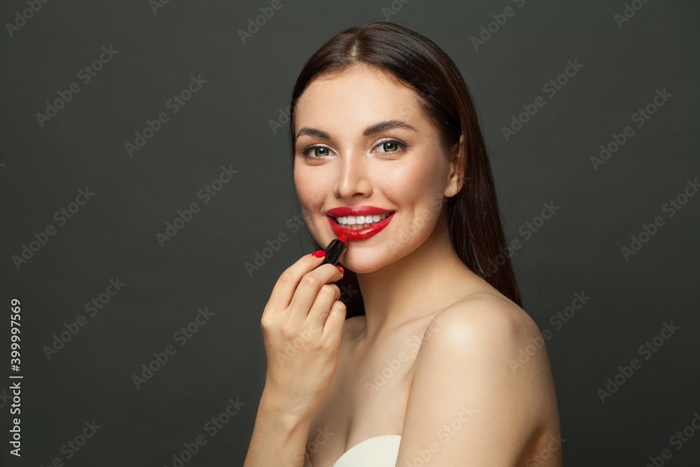 Pretty woman applying lipstick makeup on lips on black background Pretty woman applying lipstick makeup on lips on black background
