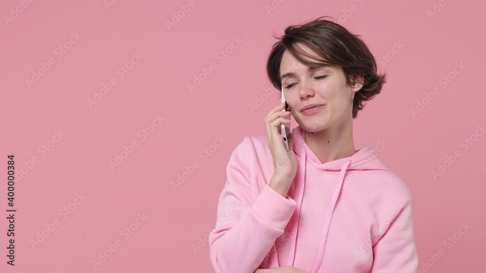 Surprised happy young woman 20s in streetwear hoodie posing isolated on pastel pink background studio. People lifestyle concept. Talking on mobile cell phone say wow doing winner gesture screaming Surprised happy young woman 20s in streetwear hoodie posing isolated on pastel pink background studio. People lifestyle concept. Talking on mobile cell phone say wow doing winner gesture screaming