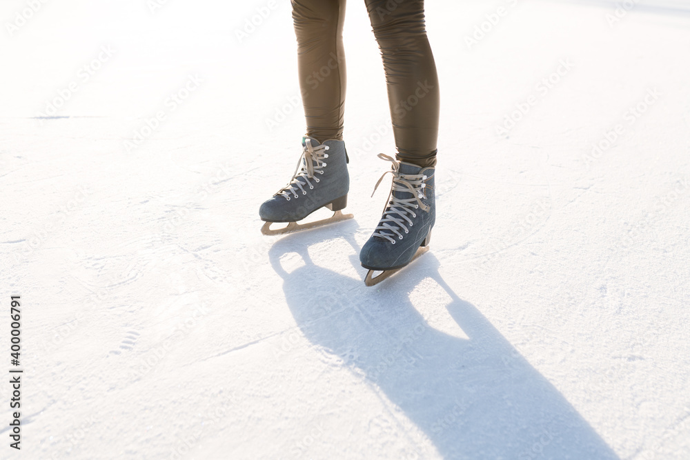 Women's legs in skates standing on the snowy ice. Winter weekend concept Women's legs in skates standing on the snowy ice. Winter weekend concept