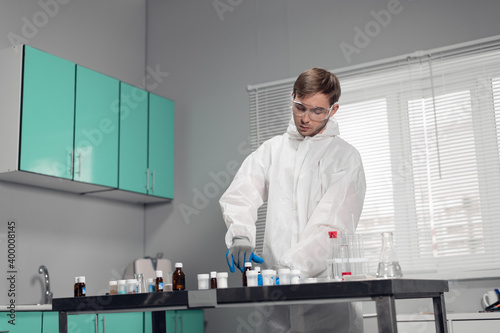 A clinician studying a new substance in a laboratory. Young handsome chemist working in the lab.