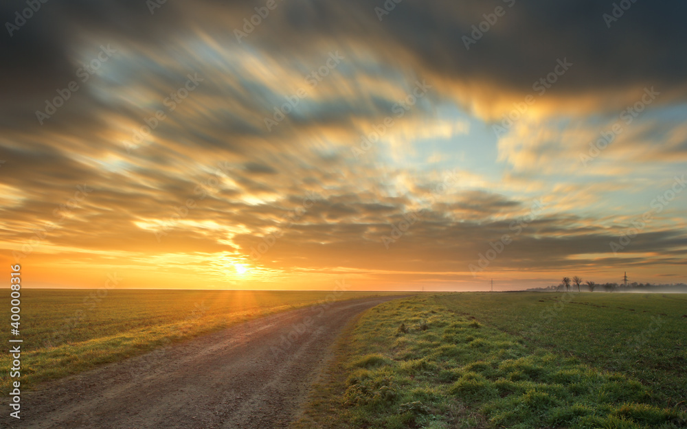 Herrlicher Sonnenaufgang auf dem Feld. Weg zur Sonne. Ein Morgen auf dem Feld. Wolkiger Himmel. Sonnenstern. 