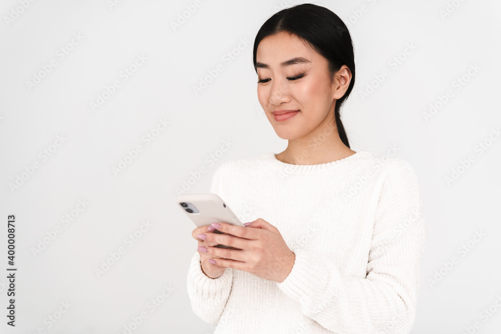 Asian pleased nice girl smiling while using mobile phone Asian pleased nice girl smiling while using mobile phone