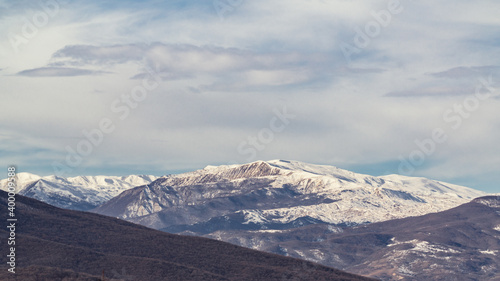 Snow capped mountains landscape, bare trees
