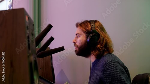 Side view of a narrator or commentator speaking his mind into a microphone. Media. Young man with headphones talking about sports event. photo