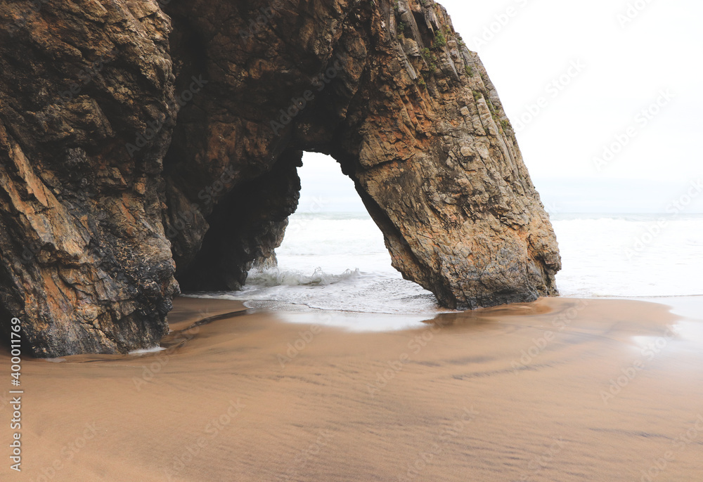 Beautiful stone natural arche. Rock formation in a beach with ocean in background.