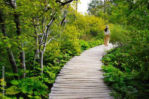 Young woman traveler walking on wooden path trail in Plitvice Lakes National Park, UNESCO natural world heritage and famous travel destination of Croatia