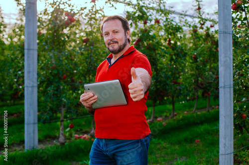 Farmer Standing in apple orchard, Looking at camera and showing thumb Up