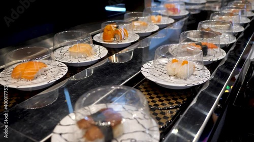 Sushi moving on conveyor belt in Japanese restaurant. Conveyor belt sushi or rotating sushi. 4K photo