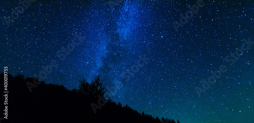 Fantastic starry night with galaxy Milky Way with a tourist and a tent on the mountain range in the Ukrainian Carpathians 