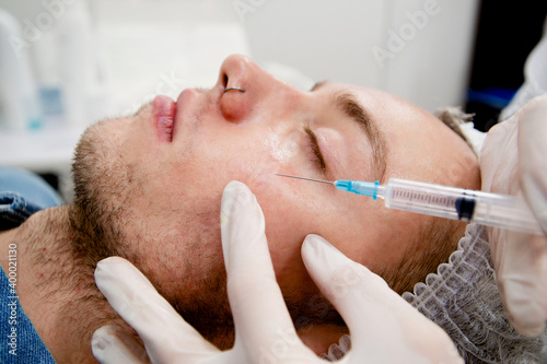 Fototapeta Naklejka Na Ścianę i Meble -  Dermatologist's making injections to man's face to remove scars and wrinkles and make it smooth and young