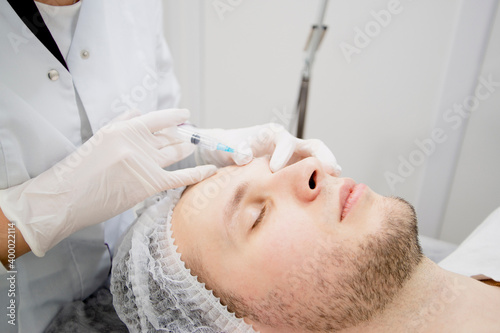Cosmetologist's making injections to man's face to remove scars and wrinkles and make it smooth