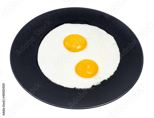 two fried eggs on black plate isolated on white background
