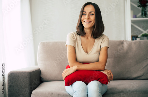 Beautiful young happy brunette woman is relaxing on the couch at home and dreaming