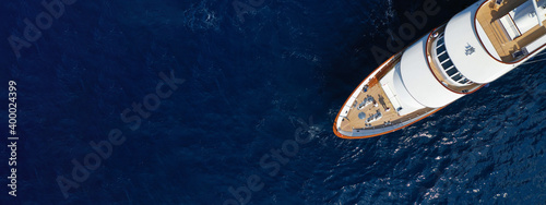 Aerial drone ultra wide photo of luxury yacht with wooden deck anchored in Mediterranean deep blue sea, Greece © aerial-drone