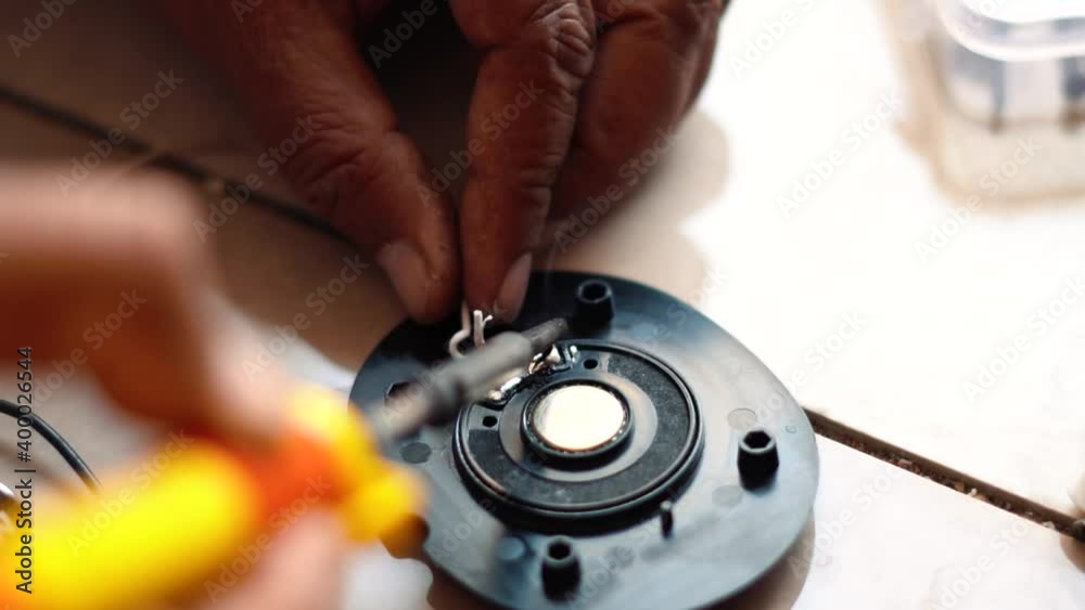 Closeup shot of hand soldering the electronic equipment to fix it. Electrician fixes the broken wire. Computer repair concept Closeup shot of hand soldering the electronic equipment to fix it. Electrician fixes the broken wire. Computer repair concept