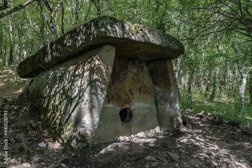 Stone dolmen in the thicket of a green forest