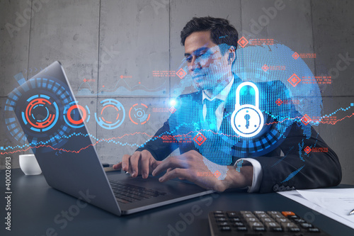 Businessman in office working with laptop, develop data protection system to diminish business risks, typing computer. Double exposure.