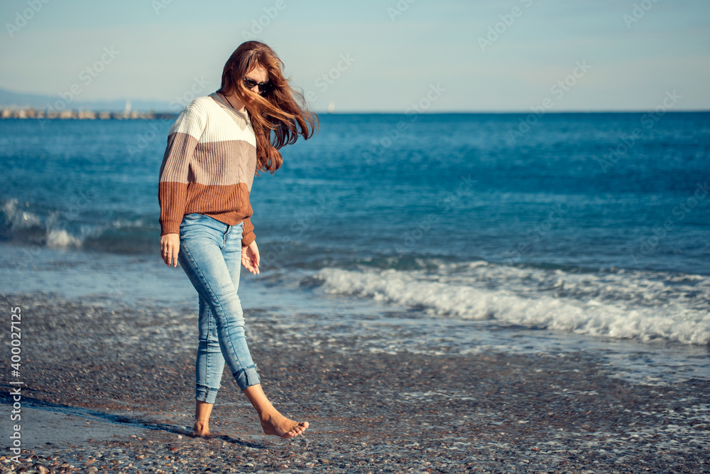 Young woman walking on the beach in winter Young woman walking on the beach in winter