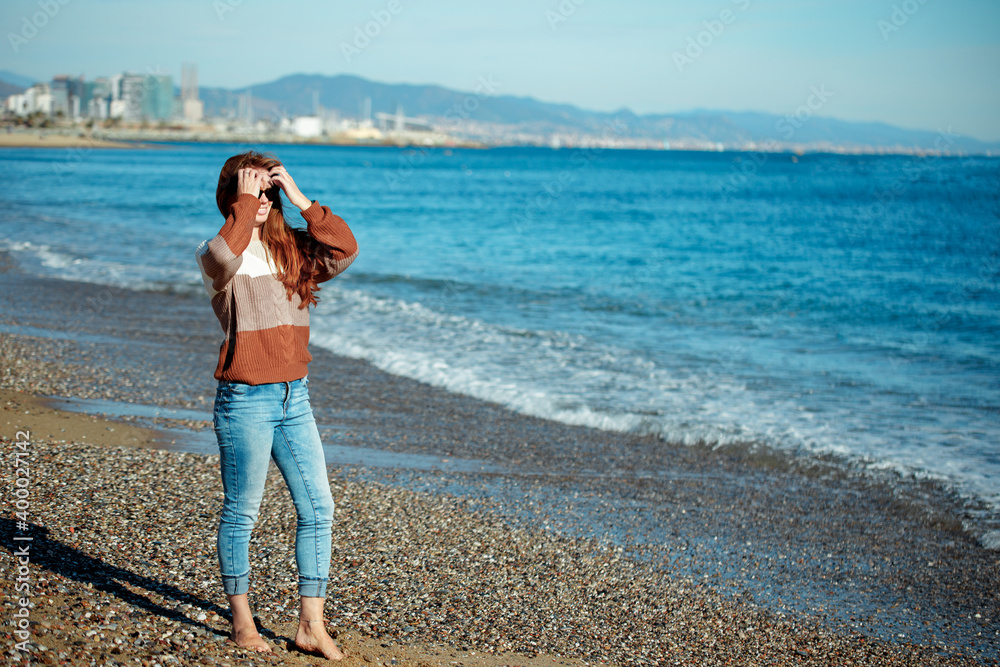 Young woman looking at sun on the beach in winter Young woman looking at sun on the beach in winter