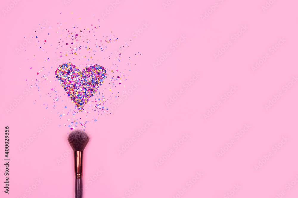 Closeup of professional cosmetic makeup brush with explosion of shiny colorful sparkles on bright pink background with copyspace for your text. Creative make-up concept - obrazy, fototapety, plakaty 