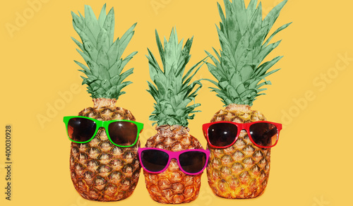 Close up of stylish small pineapple with sunglasses isolated on a blue background
