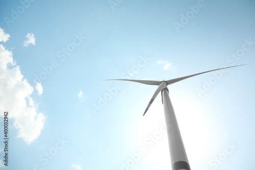 Modern wind turbine against blue sky, low angle view. Energy efficiency © New Africa