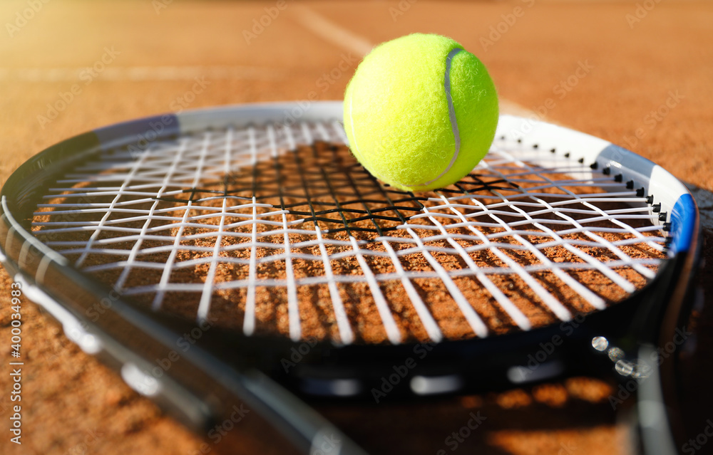Tennis ball and racket on clay court, closeup